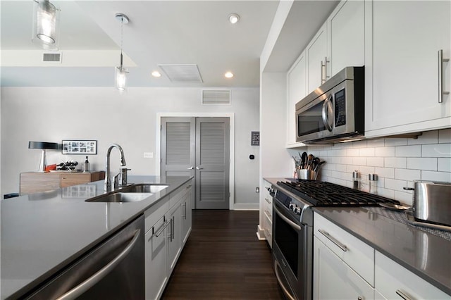 kitchen with backsplash, dark wood-type flooring, sink, white cabinetry, and stainless steel appliances