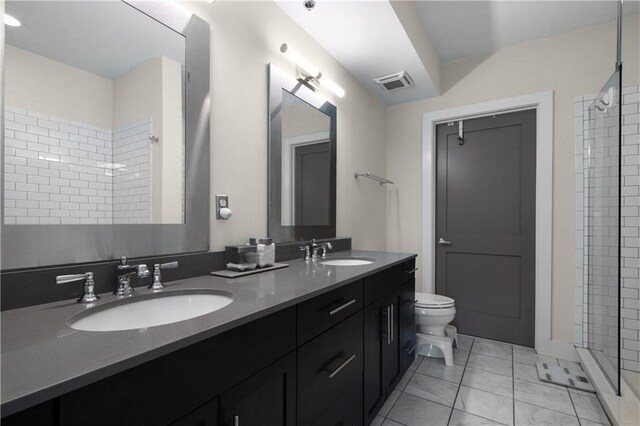 bathroom featuring tile patterned flooring, vanity, toilet, and a tile shower