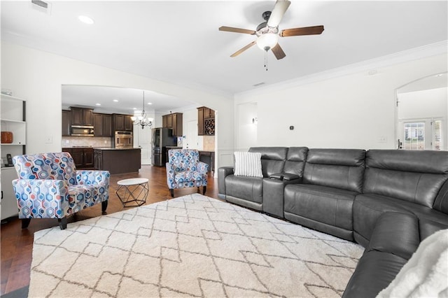 living room with crown molding, ceiling fan with notable chandelier, and dark wood-type flooring