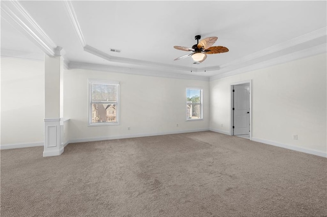 carpeted empty room with crown molding, ceiling fan, a raised ceiling, and ornate columns