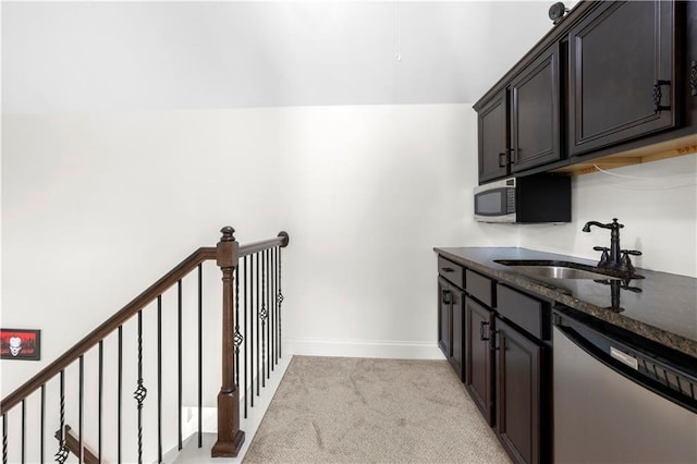 kitchen with dark brown cabinetry, sink, light carpet, dark stone countertops, and stainless steel appliances