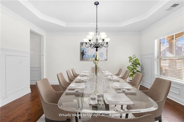 dining area featuring an inviting chandelier, a tray ceiling, dark wood-type flooring, and ornamental molding