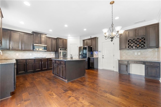 kitchen with hanging light fixtures, a kitchen island, appliances with stainless steel finishes, and dark brown cabinets