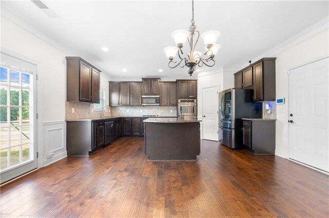 kitchen with dark brown cabinetry, tasteful backsplash, stainless steel appliances, and a kitchen island