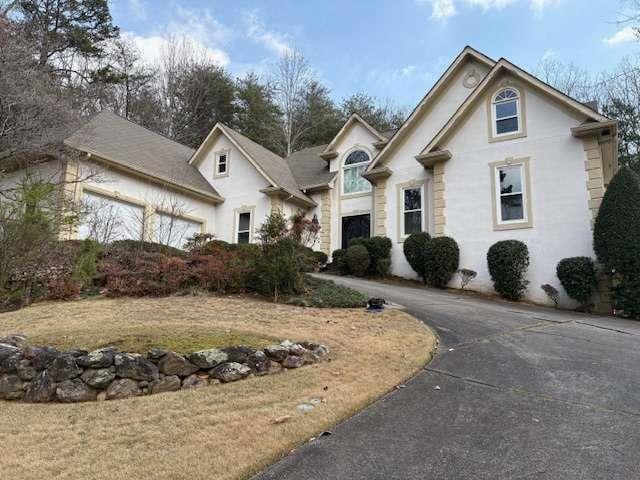 view of front facade featuring a garage, driveway, and stucco siding