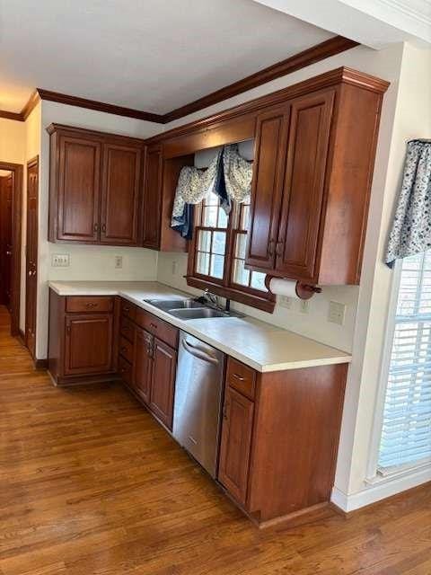 kitchen featuring light wood-type flooring, dishwasher, crown molding, and light countertops