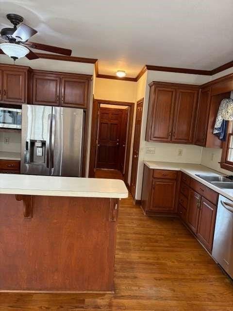 kitchen with a sink, light countertops, light wood-type flooring, and stainless steel appliances