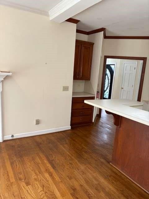 kitchen featuring dark wood-style floors, a breakfast bar area, light countertops, and crown molding