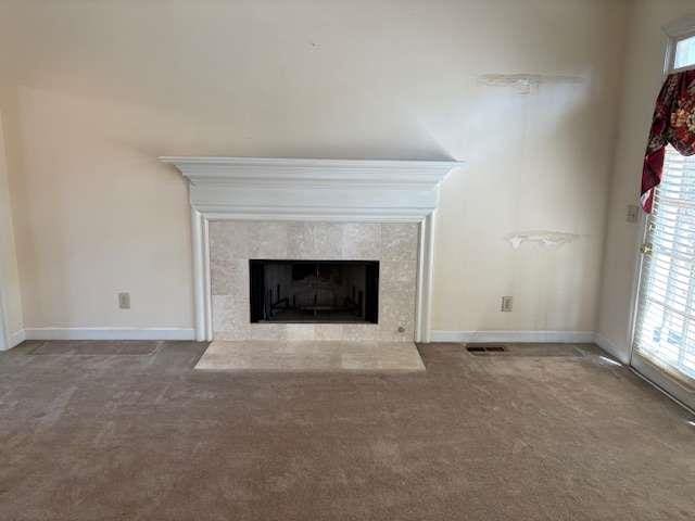 unfurnished living room with a tiled fireplace, carpet flooring, and baseboards