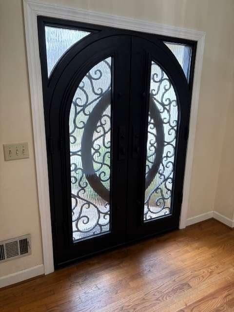 entrance foyer with arched walkways, visible vents, french doors, and wood finished floors