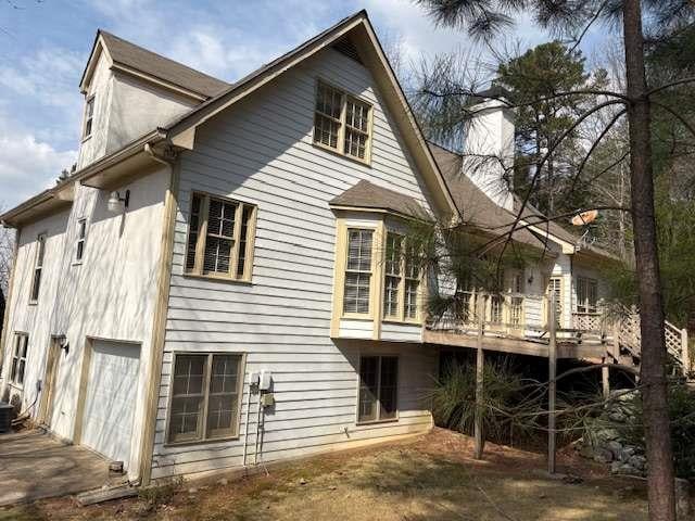 back of property featuring an attached garage and a chimney