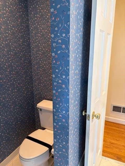 bathroom featuring visible vents, toilet, baseboards, and wood finished floors