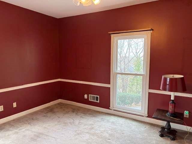 carpeted spare room featuring baseboards and visible vents