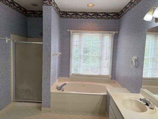 full bath featuring a stall shower, a bath, vanity, and tile patterned floors