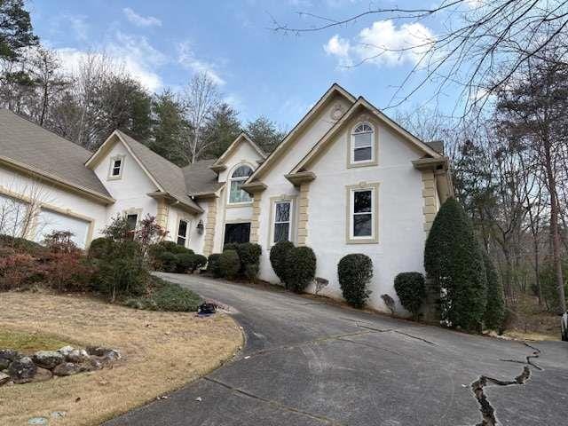 view of front facade with an attached garage, driveway, and stucco siding