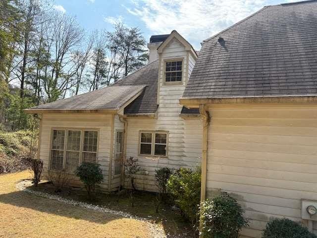 view of home's exterior with a chimney and roof with shingles