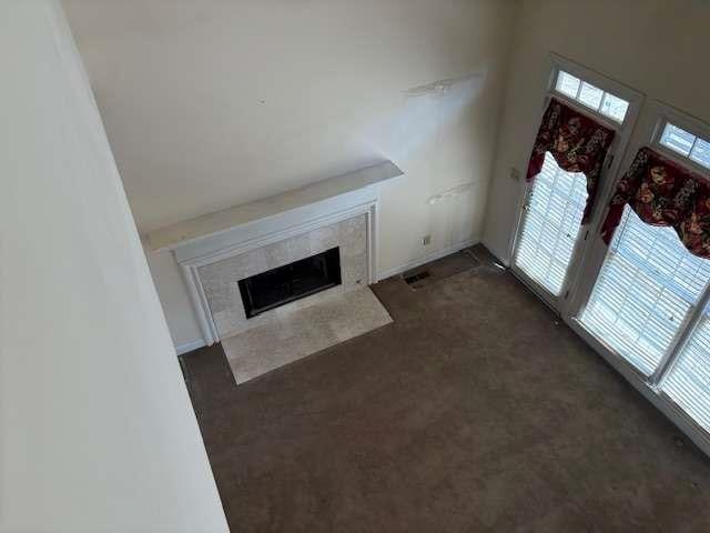 unfurnished living room featuring a premium fireplace, carpet, and visible vents