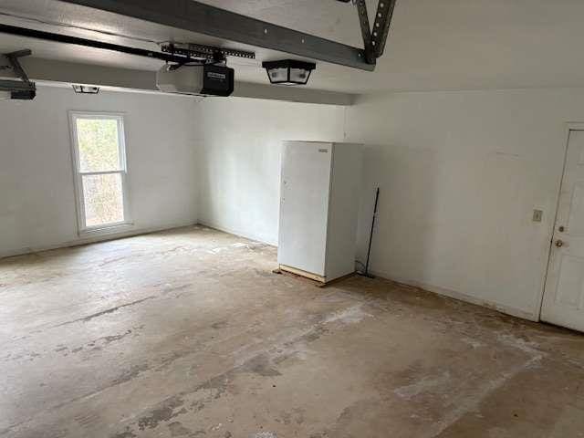 garage featuring a garage door opener and freestanding refrigerator