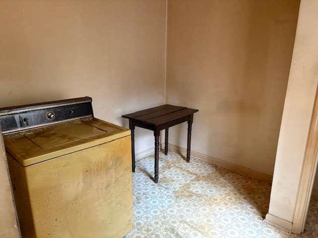 clothes washing area featuring baseboards, washer / clothes dryer, and light floors