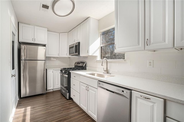 kitchen with white cabinets, appliances with stainless steel finishes, dark hardwood / wood-style floors, and sink