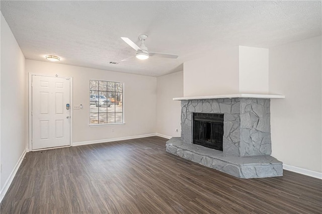 unfurnished living room featuring ceiling fan, a fireplace, dark wood-type flooring, and a textured ceiling