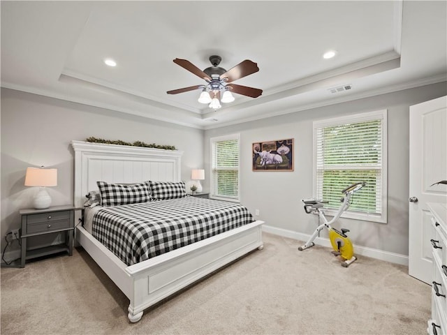 carpeted bedroom with a raised ceiling, ceiling fan, and multiple windows