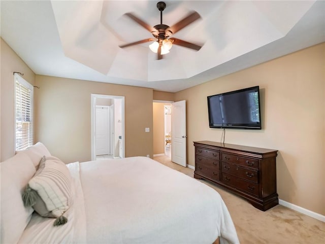 bedroom featuring a tray ceiling, light carpet, baseboards, and ceiling fan