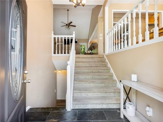 staircase with a ceiling fan, a towering ceiling, and stone finish flooring