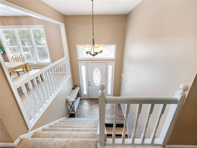 entryway featuring a chandelier, stairway, and carpet flooring