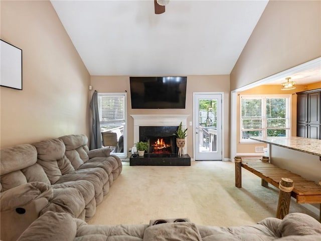 living room featuring vaulted ceiling, light colored carpet, a premium fireplace, and a ceiling fan