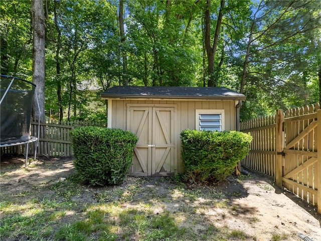 view of shed with a trampoline and a fenced backyard