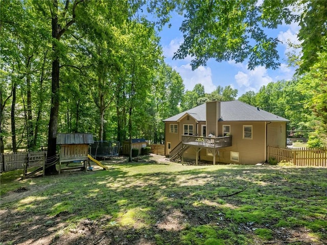 rear view of property with a fenced backyard, a deck, stairs, a playground, and a shed