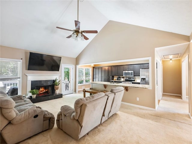living room with high vaulted ceiling, a ceiling fan, healthy amount of natural light, light colored carpet, and attic access