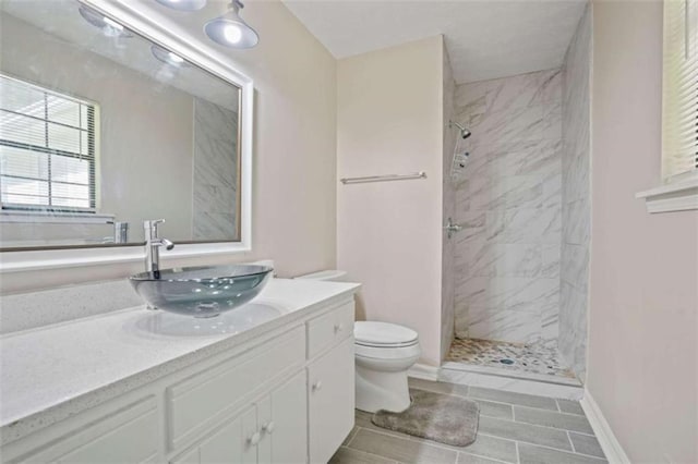 bathroom with tile patterned floors, vanity, toilet, and a tile shower