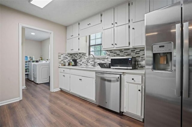 kitchen with stainless steel appliances, white cabinetry, washer and dryer, and sink