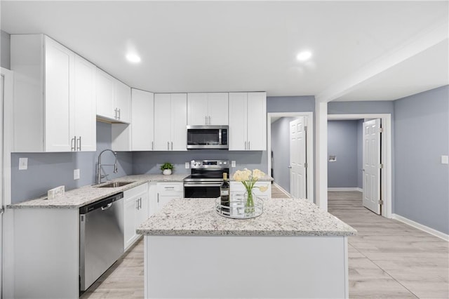 kitchen with white cabinetry, sink, stainless steel appliances, and a kitchen island