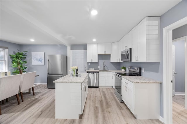 kitchen featuring a kitchen island, appliances with stainless steel finishes, white cabinets, and light stone counters