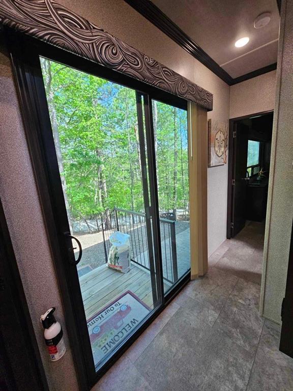 doorway with ornamental molding and tile patterned flooring