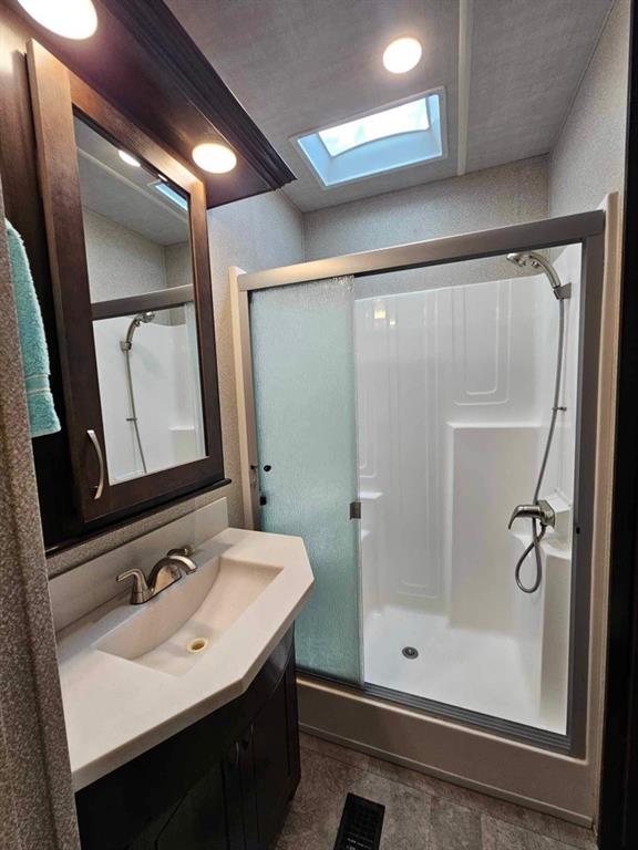 bathroom with a skylight, vanity, tile patterned floors, and walk in shower