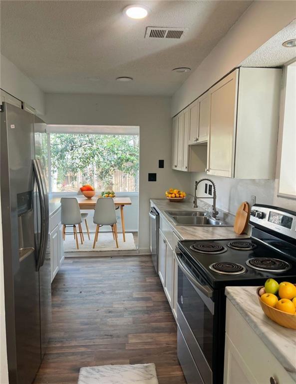 kitchen featuring sink, a textured ceiling, dark hardwood / wood-style floors, stainless steel appliances, and white cabinets