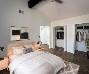 bedroom featuring ceiling fan, dark wood-type flooring, lofted ceiling with beams, and multiple closets