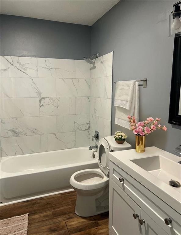 full bathroom featuring toilet, hardwood / wood-style flooring, tiled shower / bath, and vanity