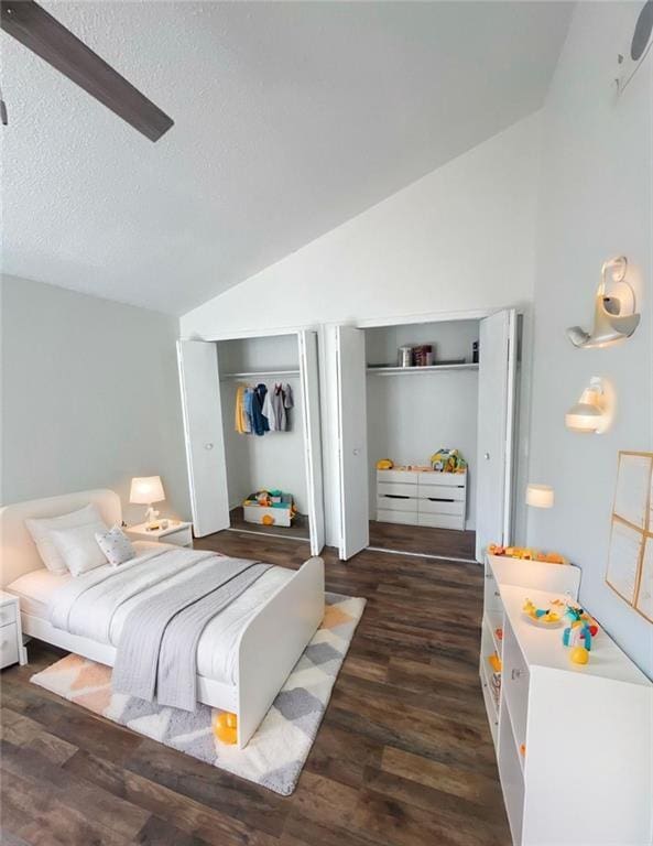 bedroom featuring dark hardwood / wood-style flooring, two closets, vaulted ceiling, and a textured ceiling