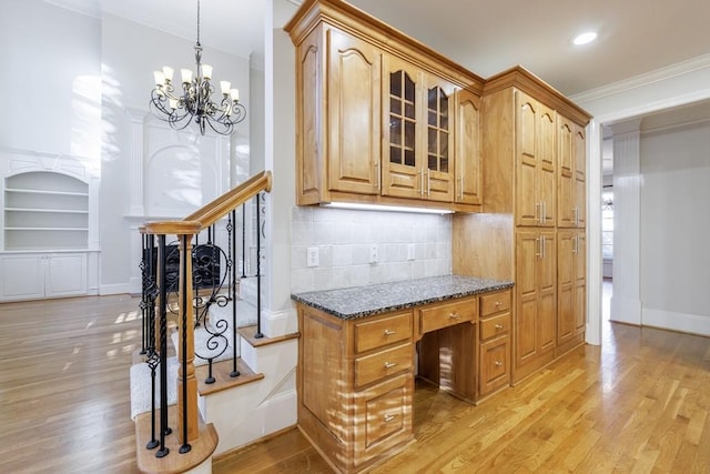 kitchen with tasteful backsplash, a notable chandelier, dark stone countertops, light hardwood / wood-style floors, and ornamental molding