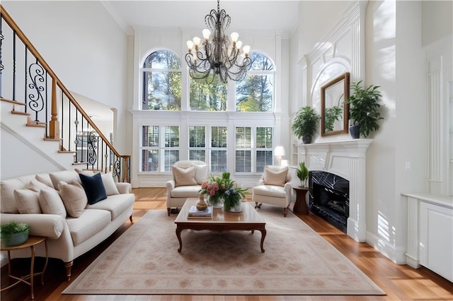 living room with light hardwood / wood-style flooring, a towering ceiling, and an inviting chandelier