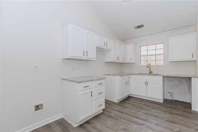 kitchen featuring sink, light hardwood / wood-style flooring, light stone counters, white cabinets, and vaulted ceiling