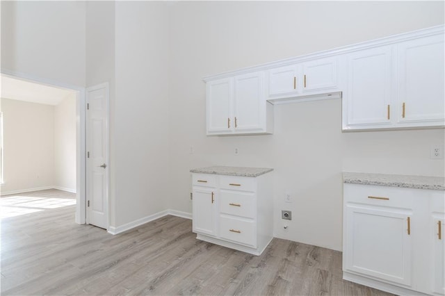 kitchen featuring white cabinetry, light stone counters, and light hardwood / wood-style flooring