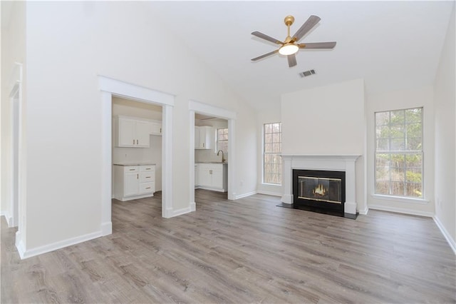 unfurnished living room with ceiling fan, plenty of natural light, sink, and light hardwood / wood-style flooring