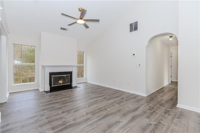 unfurnished living room with high vaulted ceiling, ceiling fan, and light wood-type flooring