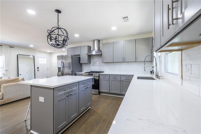 kitchen with visible vents, gray cabinetry, appliances with stainless steel finishes, a sink, and wall chimney exhaust hood